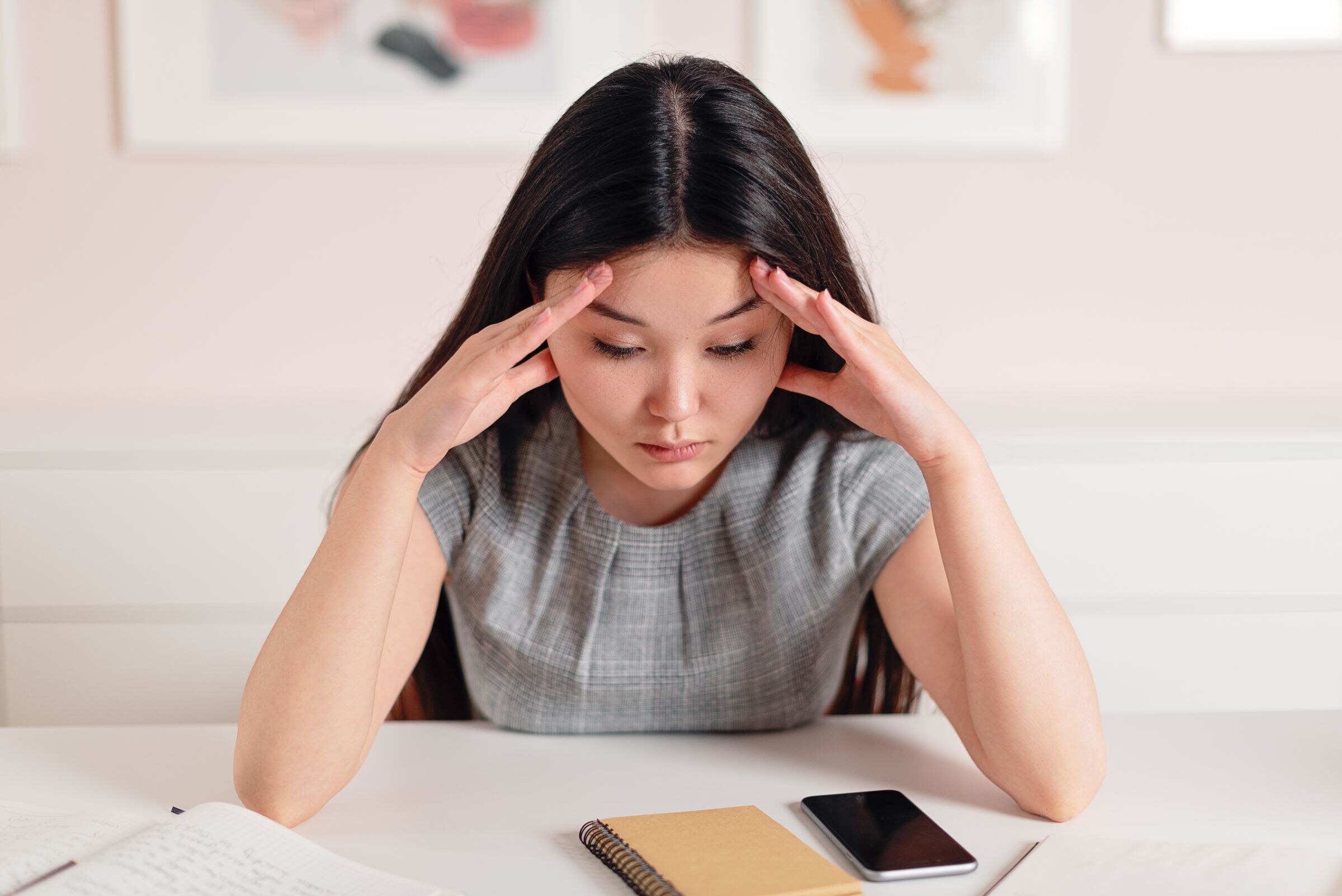 Een vrouw zit met haar hoofd in haar handen aan tafel